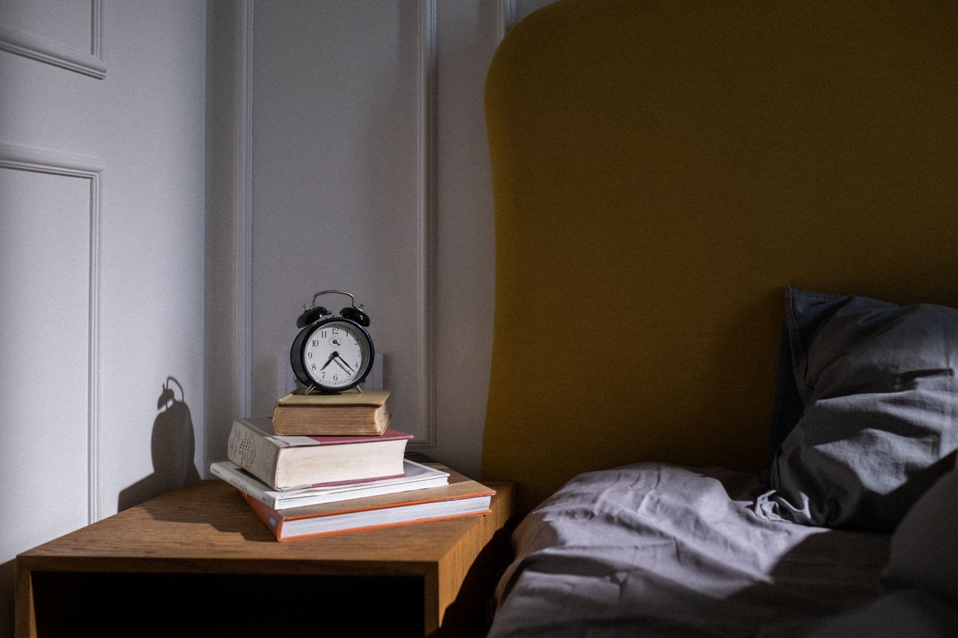 An alarm clock sitting on a sunlit bedside table