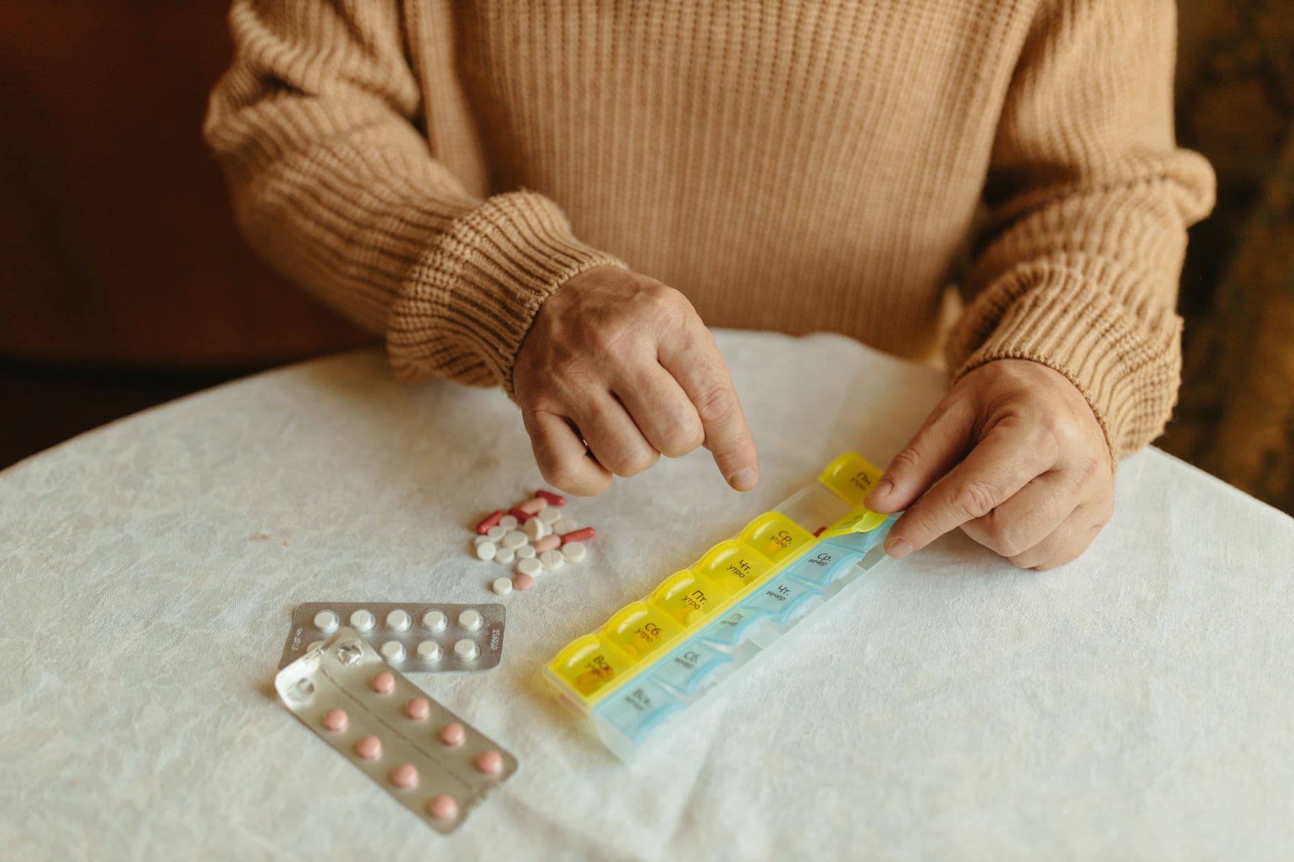 A pill organiser next to several medicine boxes
