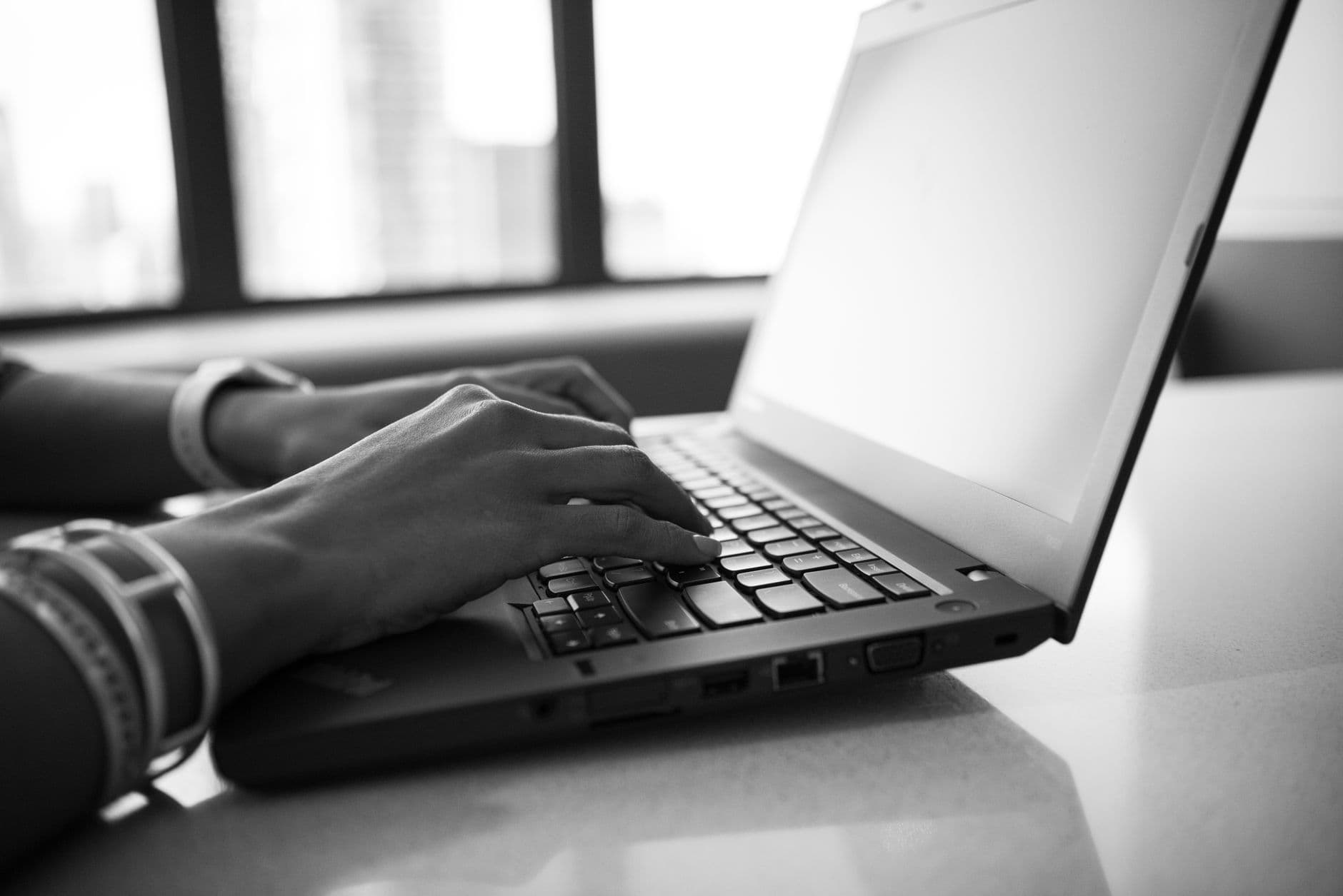 A woman typing quickly on a laptop in an office