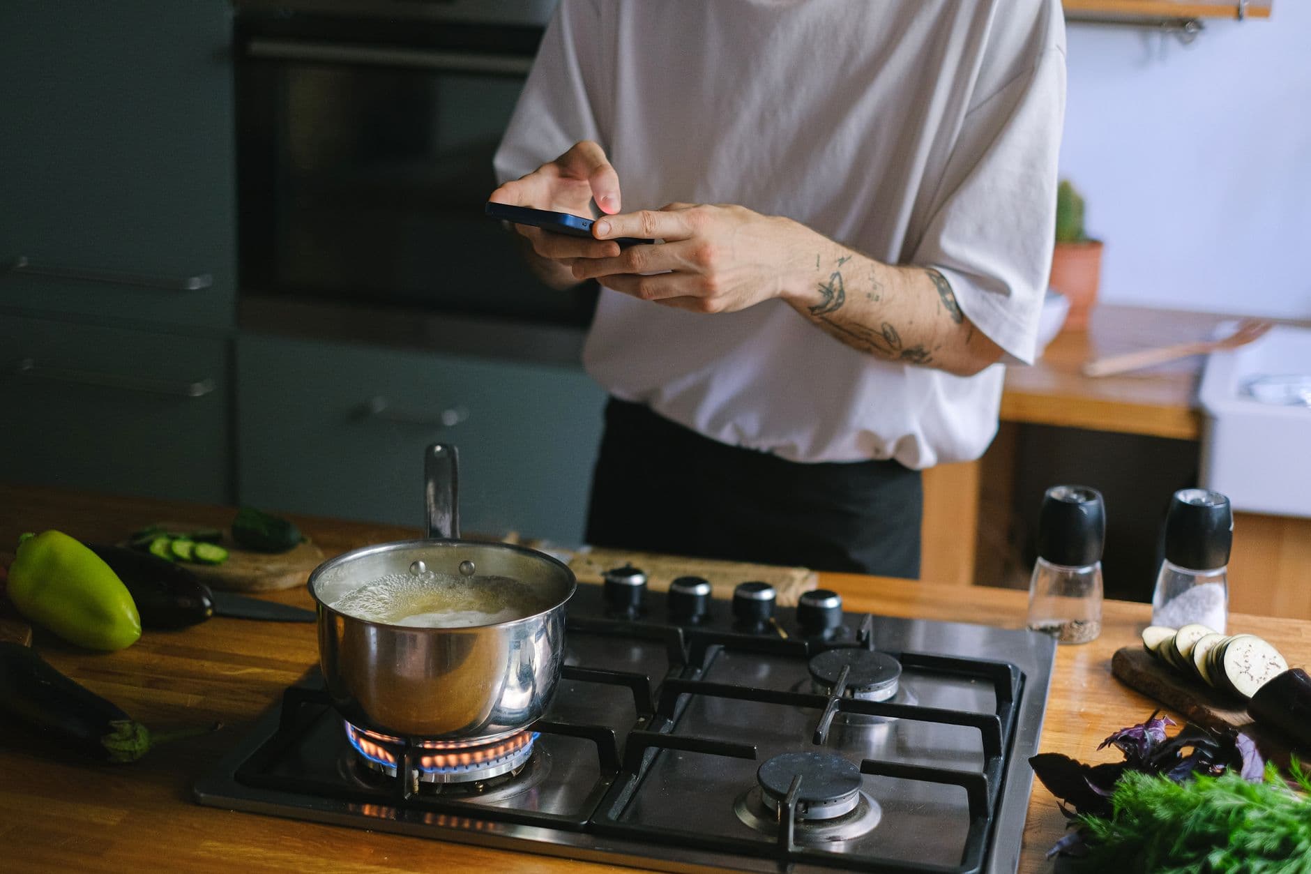 A woman cooking dinner with her phone on the counter