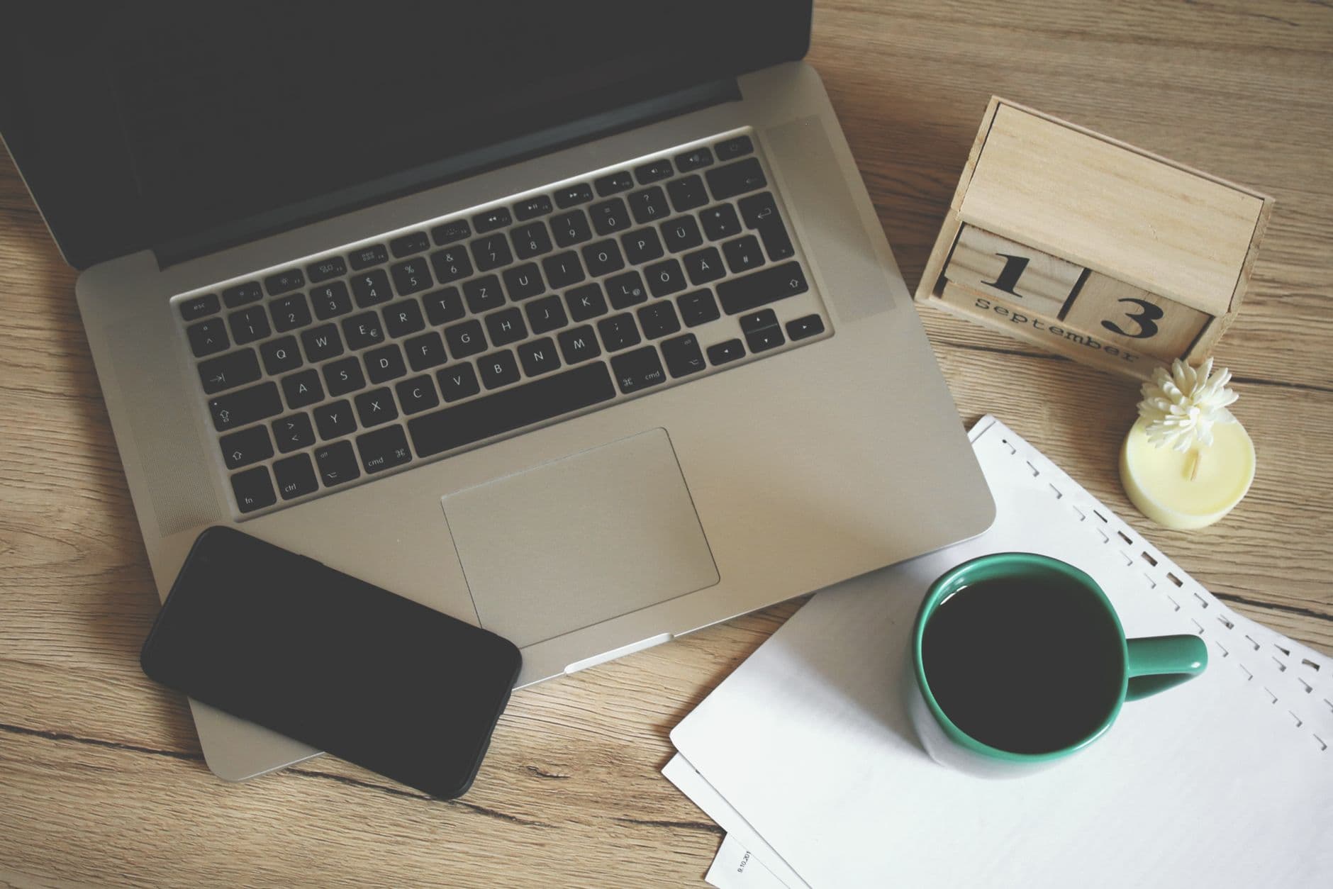 A paper calendar open beside a laptop