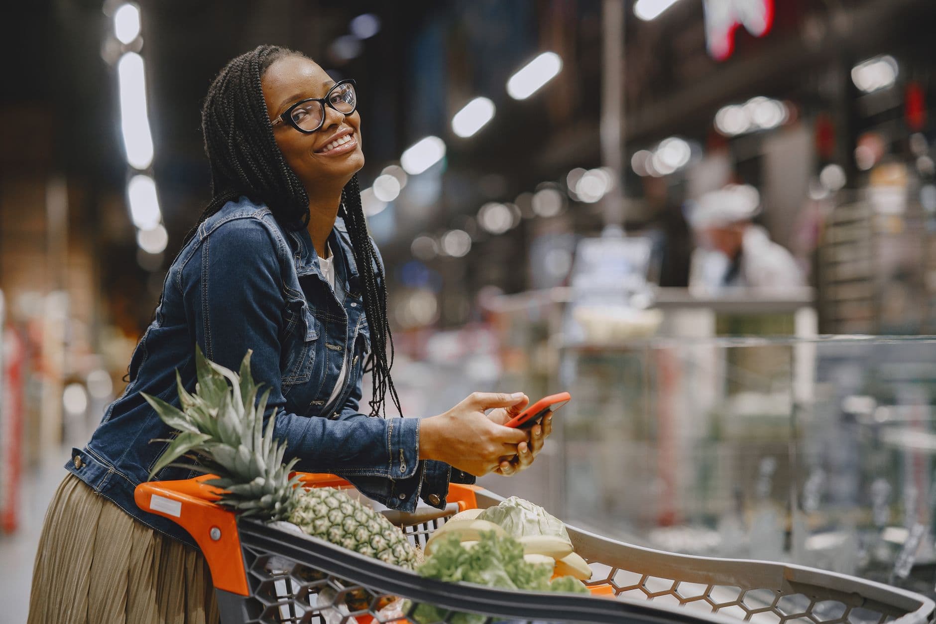 A shopping trolley in a supermarket aisle beside a smartphone