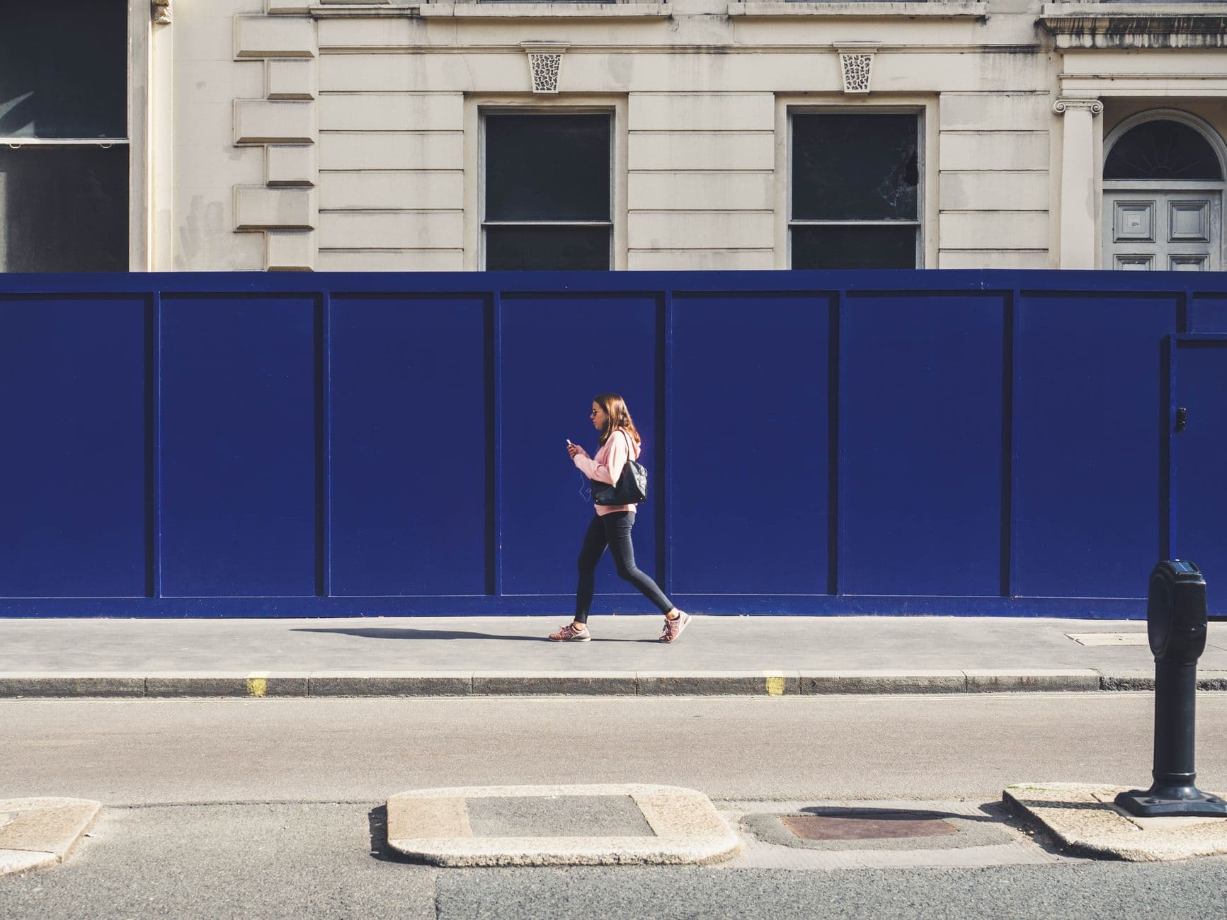Someone walking down a city street holding a smartphone