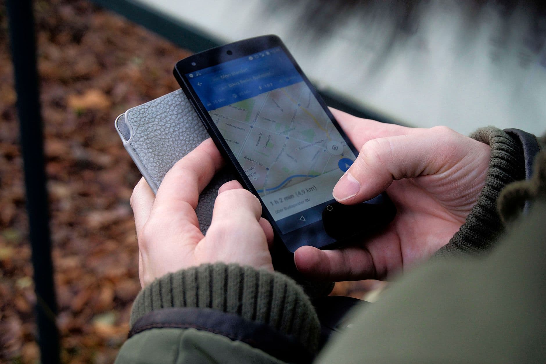 A hand holding a smartphone showing map navigation outdoors