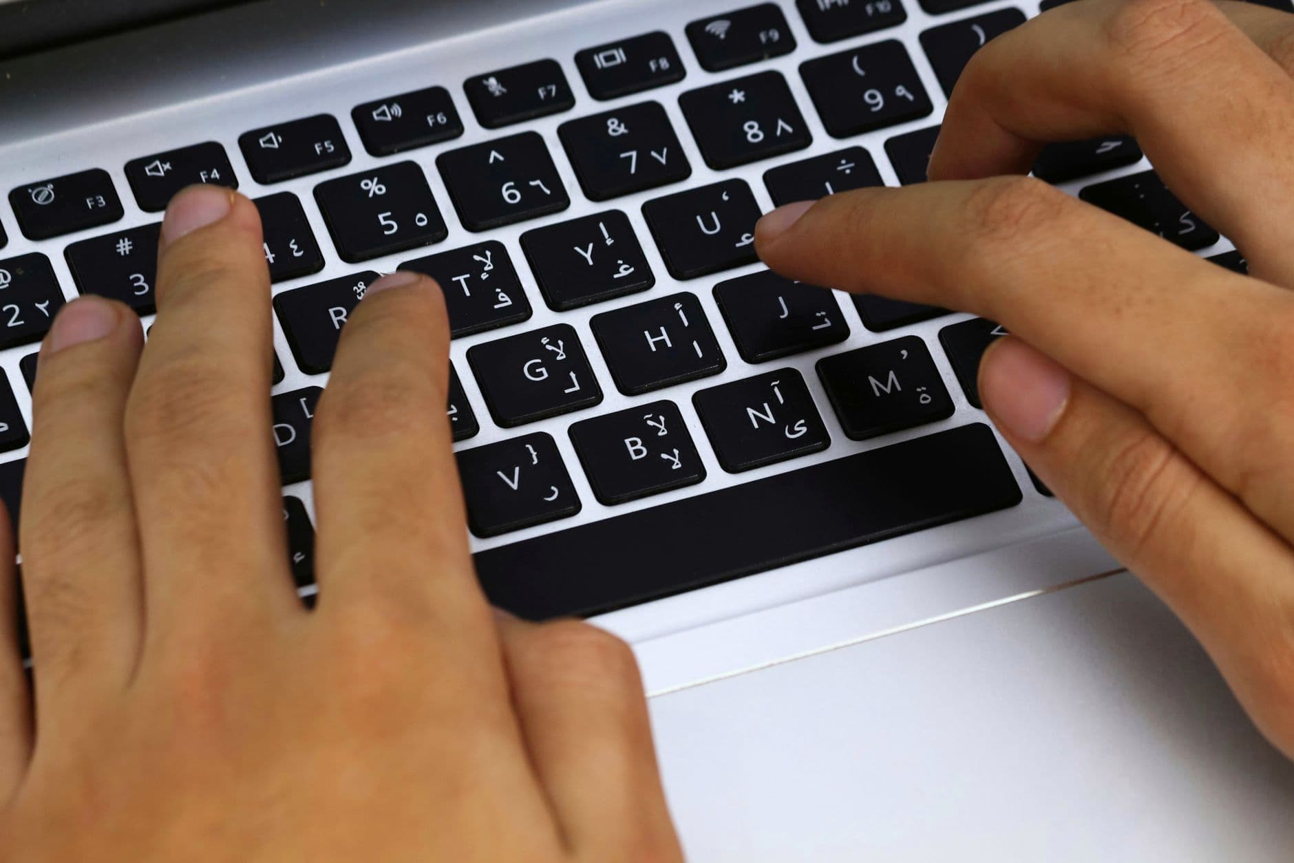 Hands typing quickly on a laptop keyboard