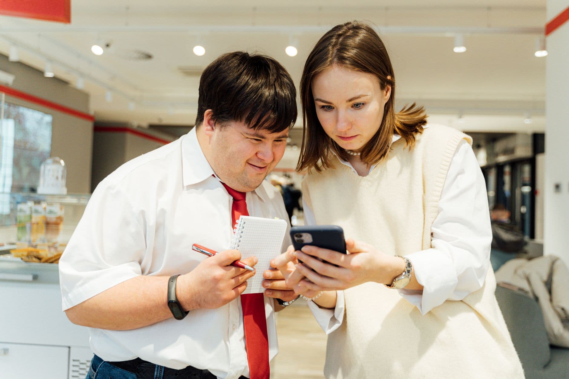 Two colleagues looking at a smartphone together in an office