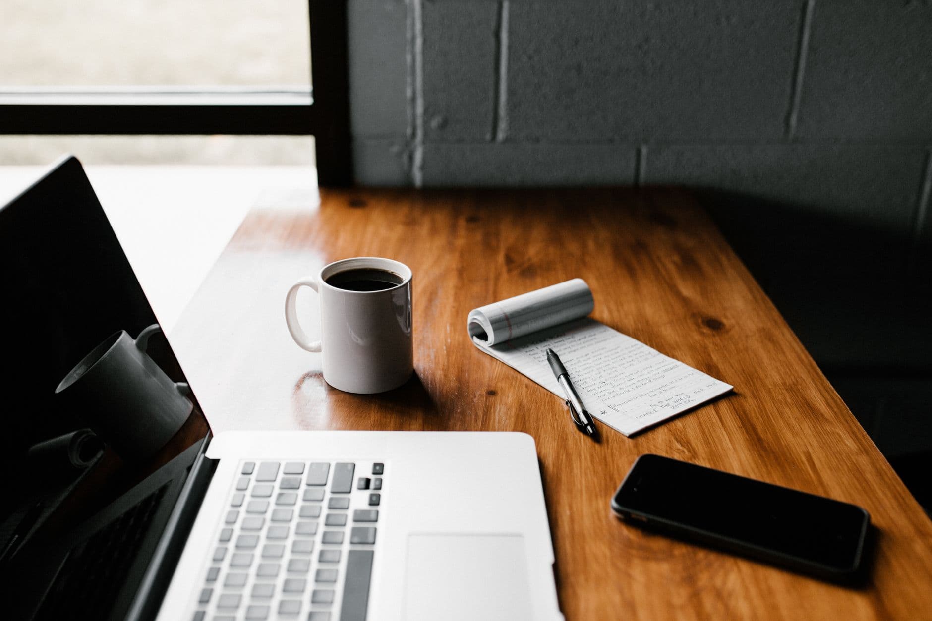 A notepad checklist beside a laptop and phone
