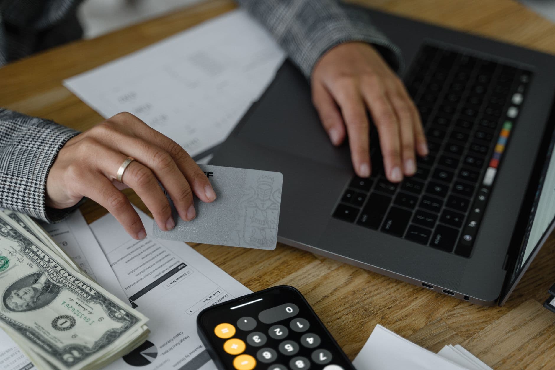 A woman going through paper bills at a kitchen table