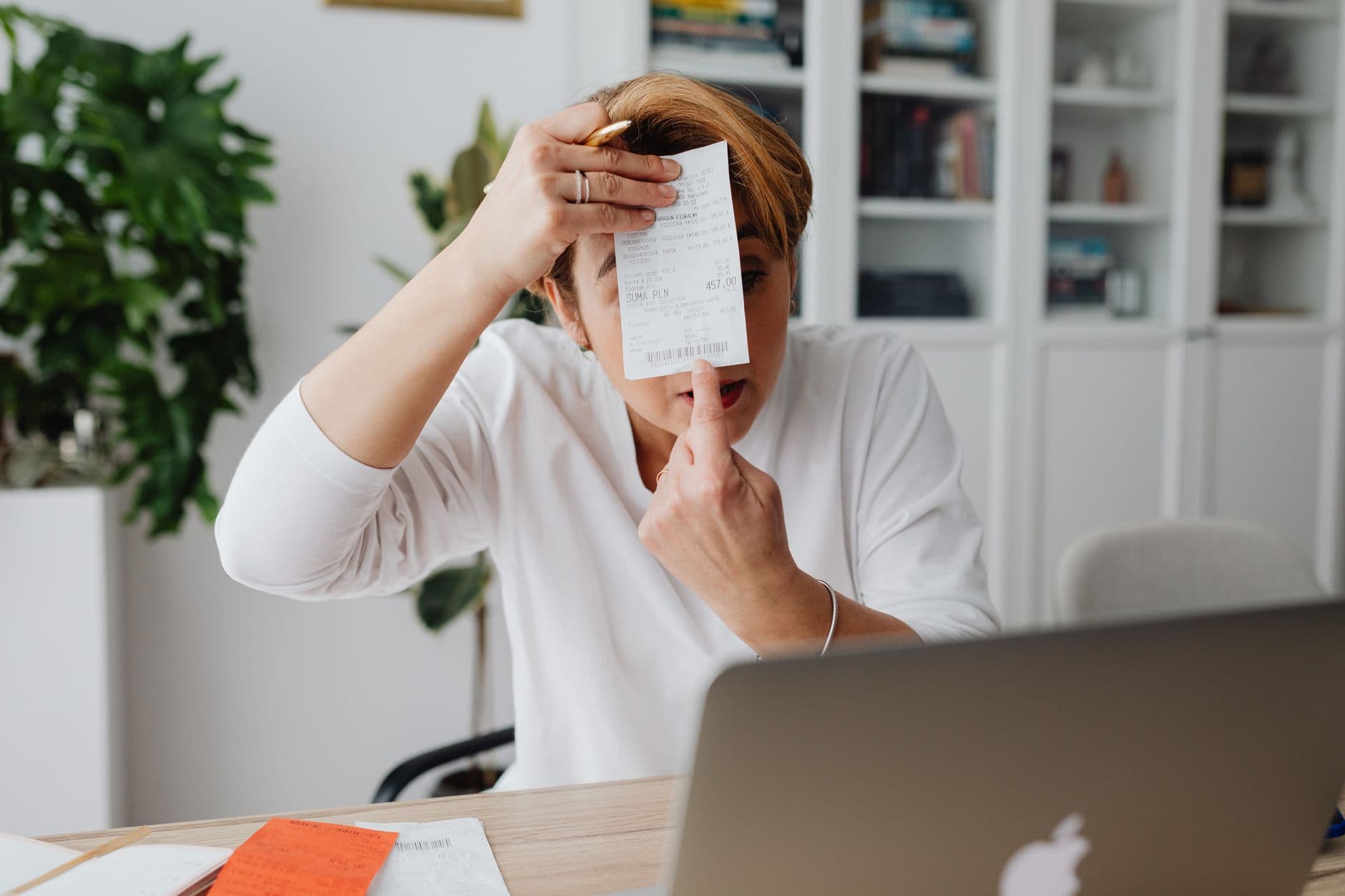 A freelancer working at a laptop surrounded by invoices