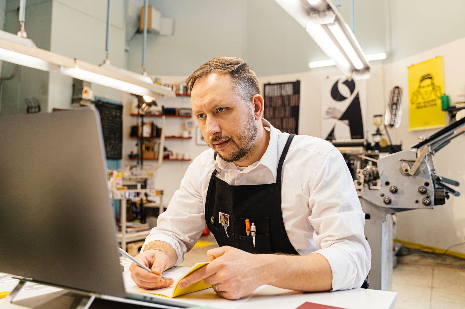 A shop owner working at a laptop in a back office