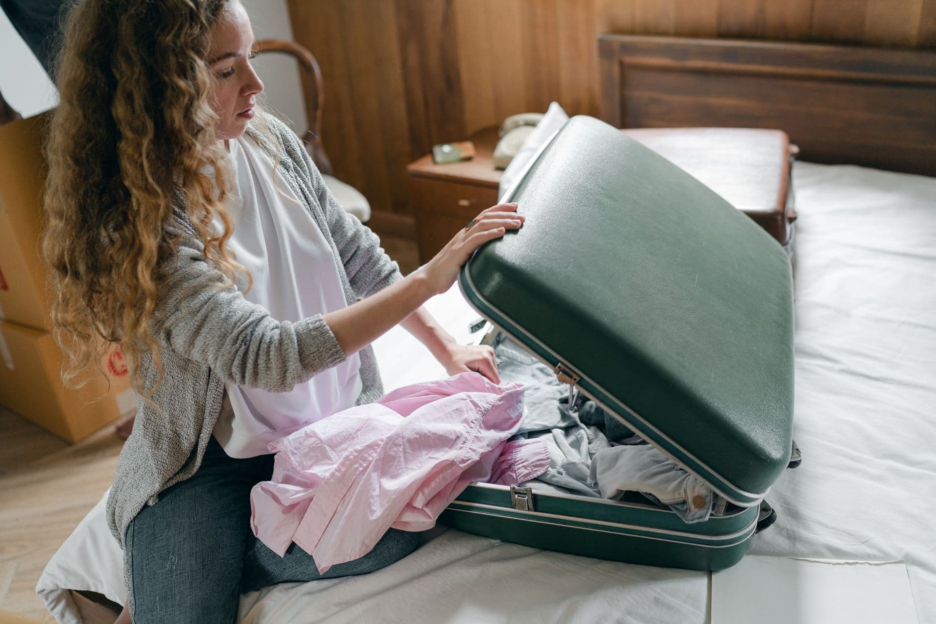 A woman packing clothes into a suitcase in a bedroom