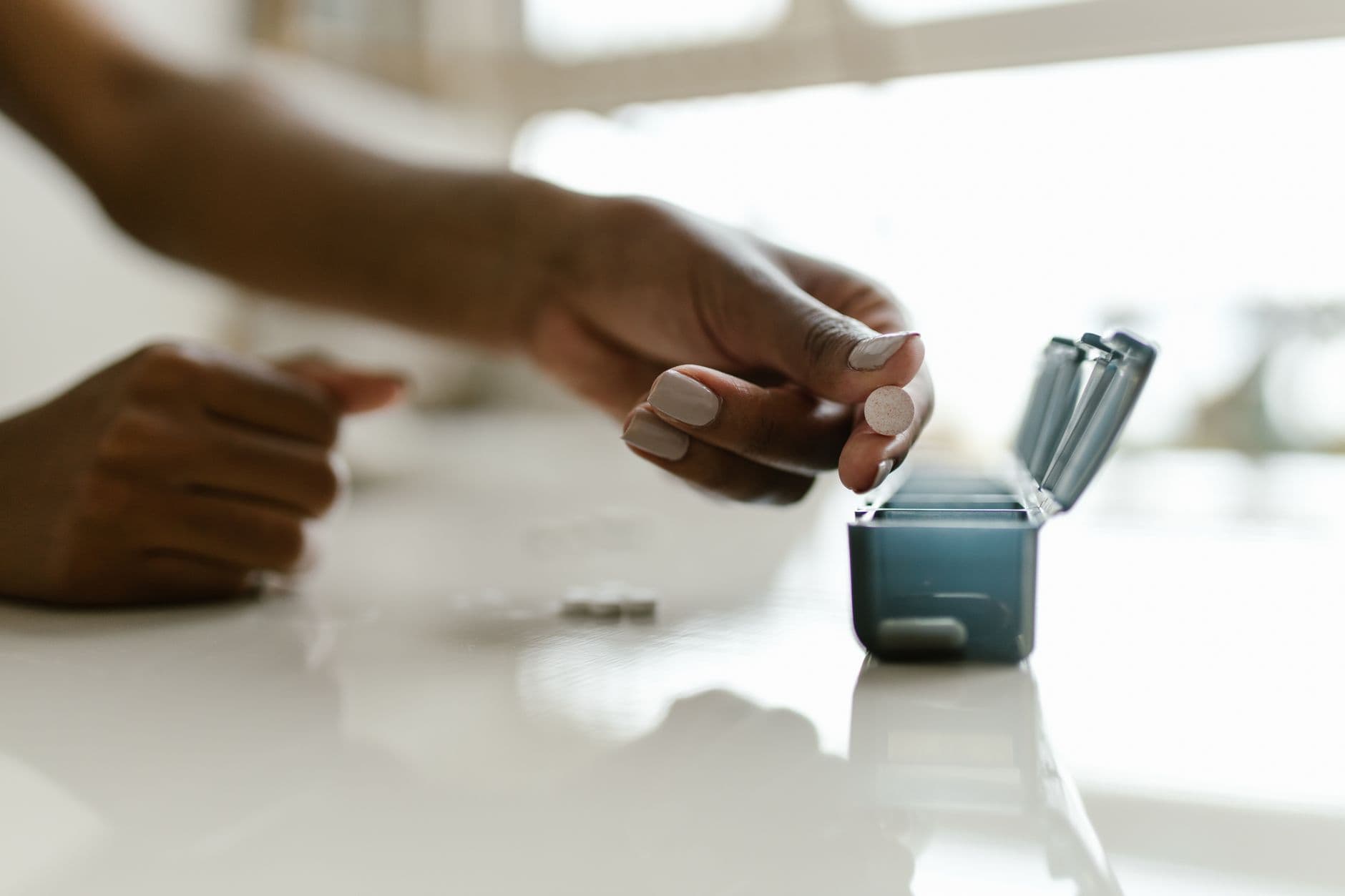 A weekly pill organizer open on a kitchen counter