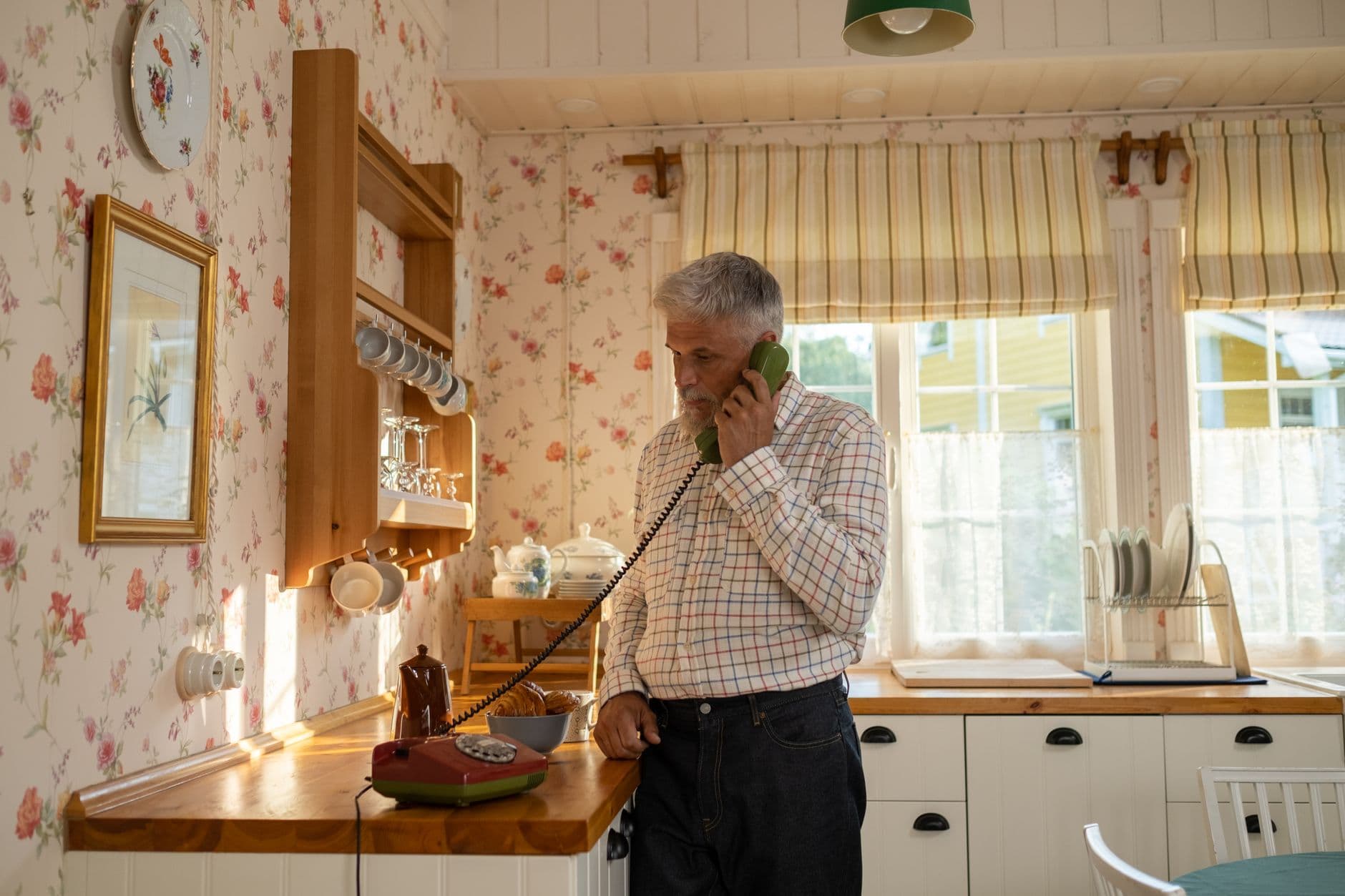 An older woman answering a landline telephone at home