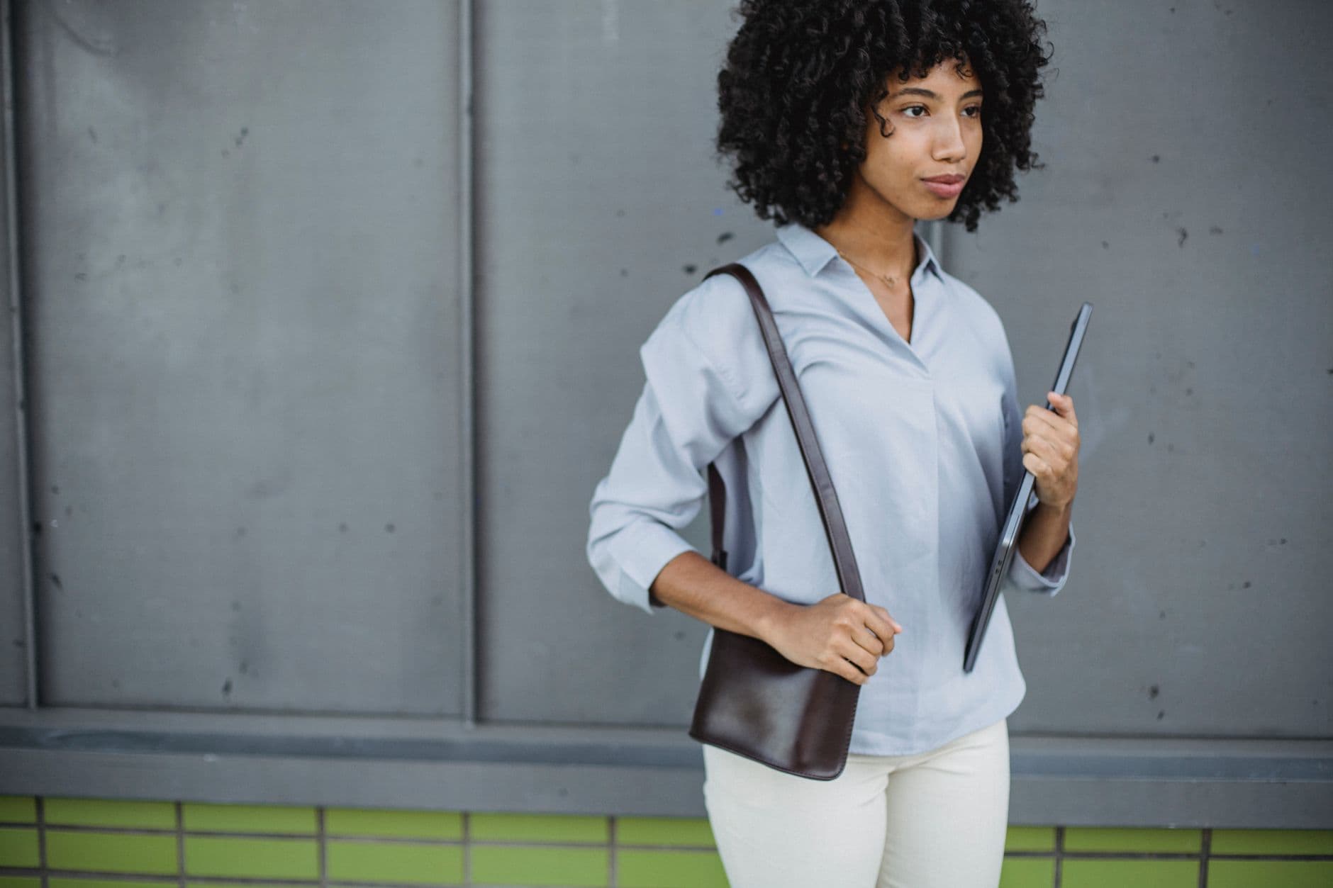 Someone checking their phone outdoors while carrying a laptop bag