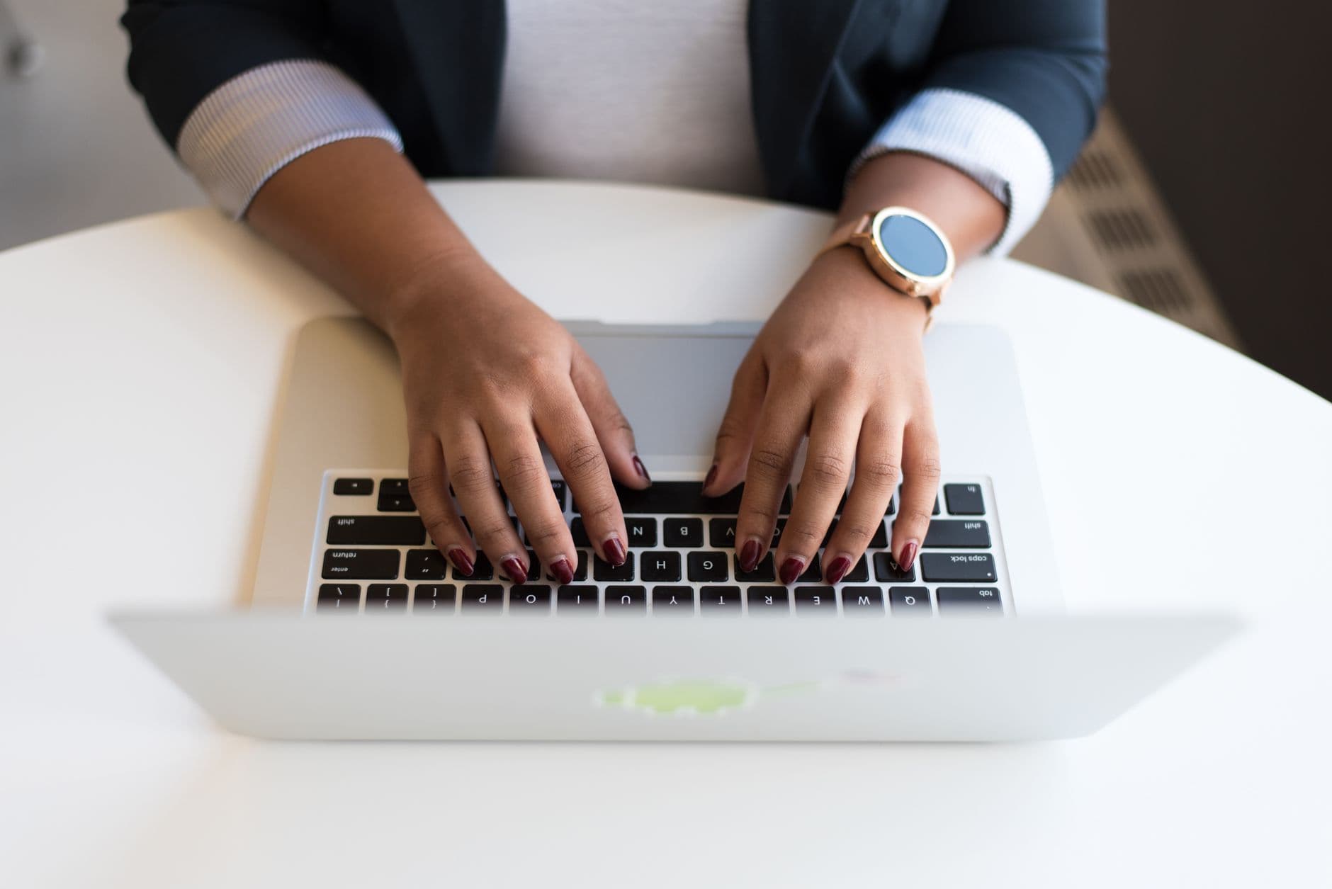 A woman typing an email on a laptop at a desk