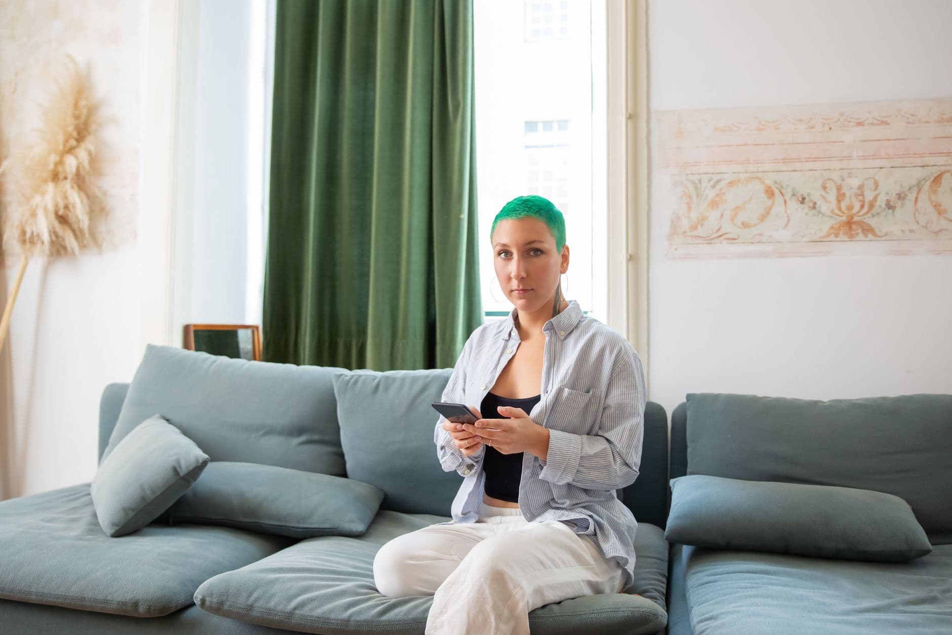 A woman sitting on a sofa looking at her smartphone